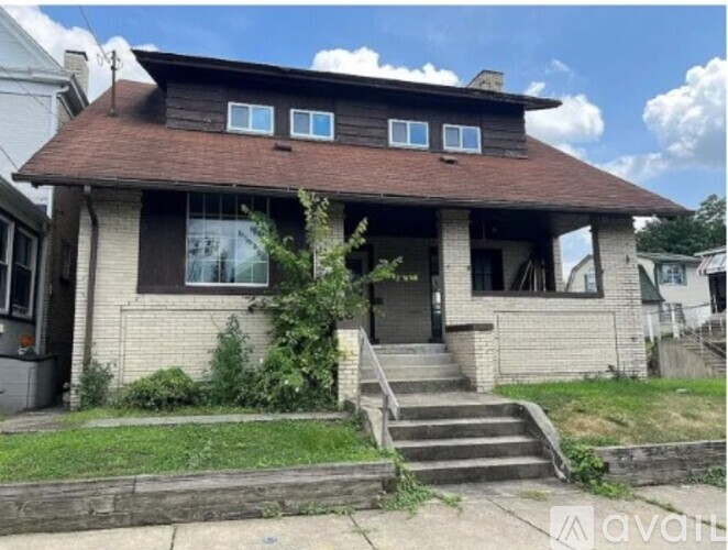 A house with a brown roof and a front porch with stairs leading up to it.