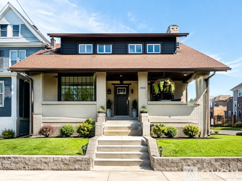 A house with a brown roof and a front porch with stairs leading up to it.