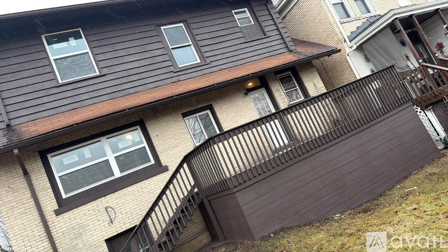 A house with a brown wooden deck and a staircase leading to the second floor.