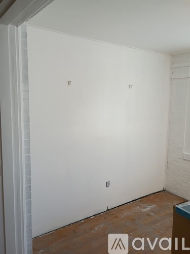 A room with white walls and wooden flooring, with a logo that reads "avaiL" in the bottom right corner.