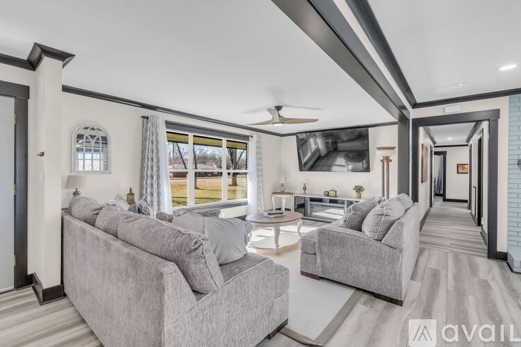 A living room with grey couches and a white ceiling fan.