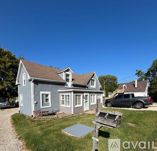 A house with a grey roof and a sign that says "available" in front of it.