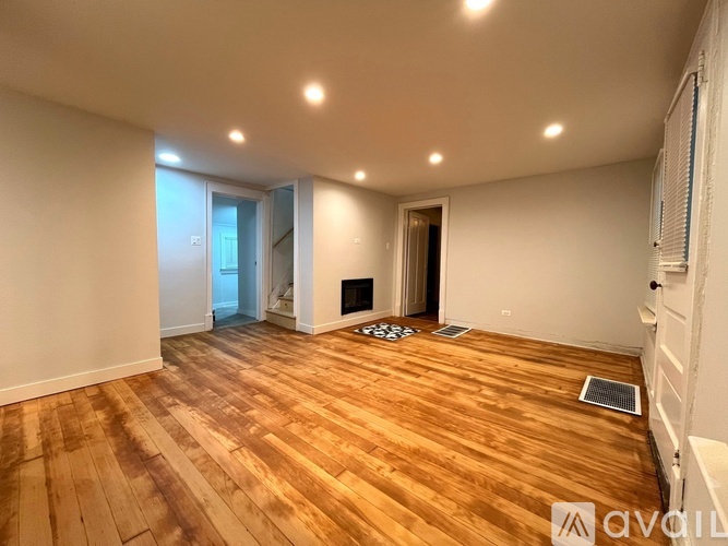 A room with wooden flooring and a fireplace.