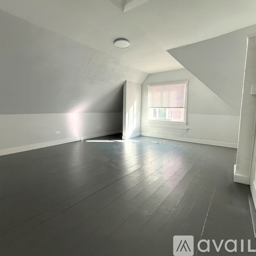 A spacious room with wooden flooring and white walls.