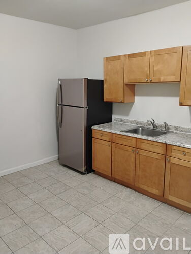 A kitchen with a refrigerator, cabinets, and a sink.