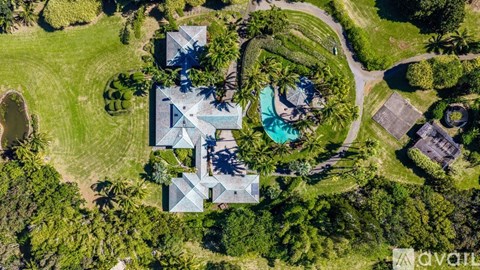 A bird's eye view of a house surrounded by greenery and a pool.
