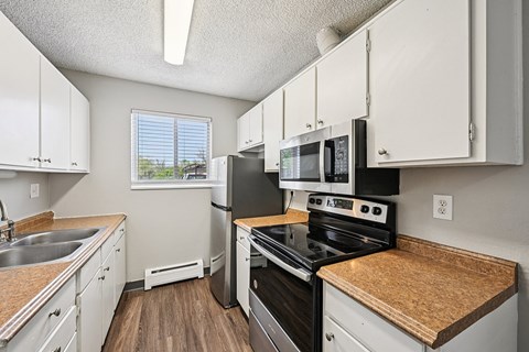 A white refrigerator in a kitchen with wooden floors.
