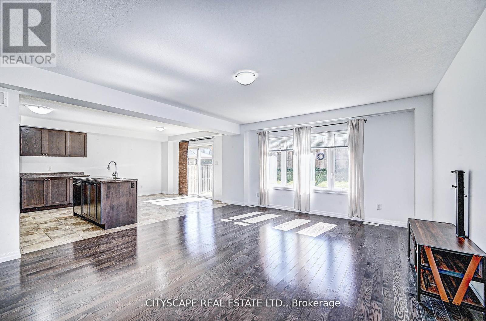 A spacious living room with wooden floors and a large window.