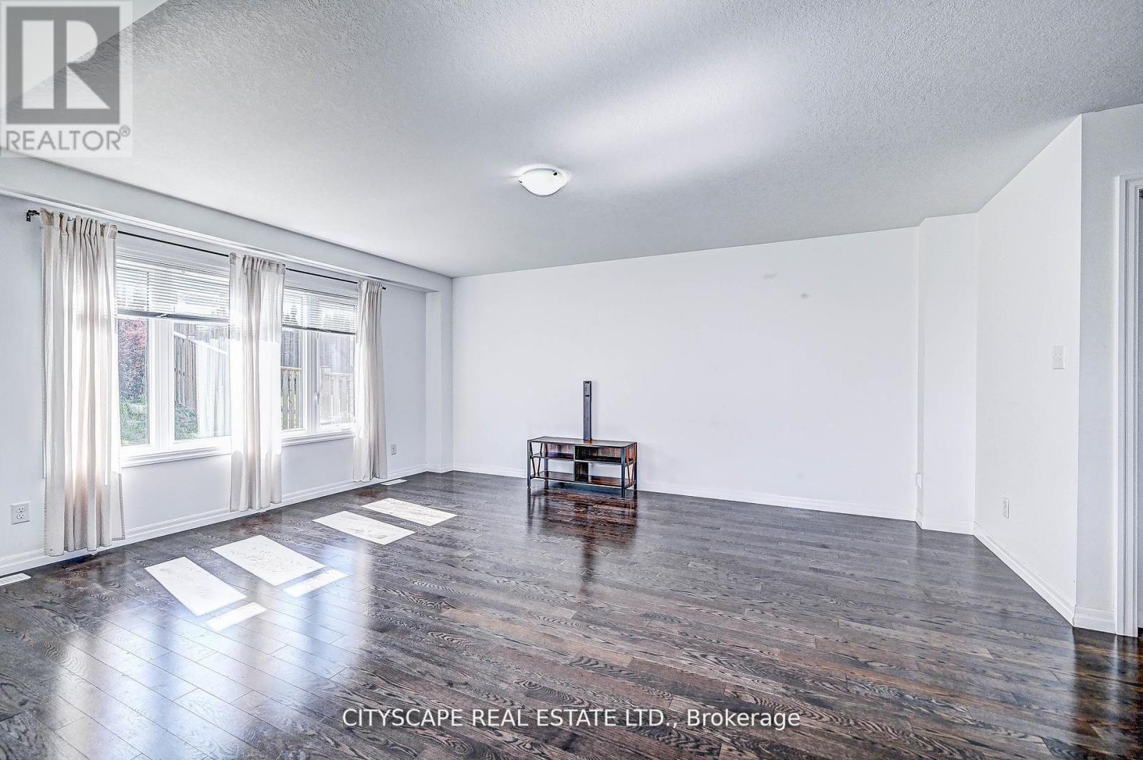 A spacious room with wooden floors and white walls.