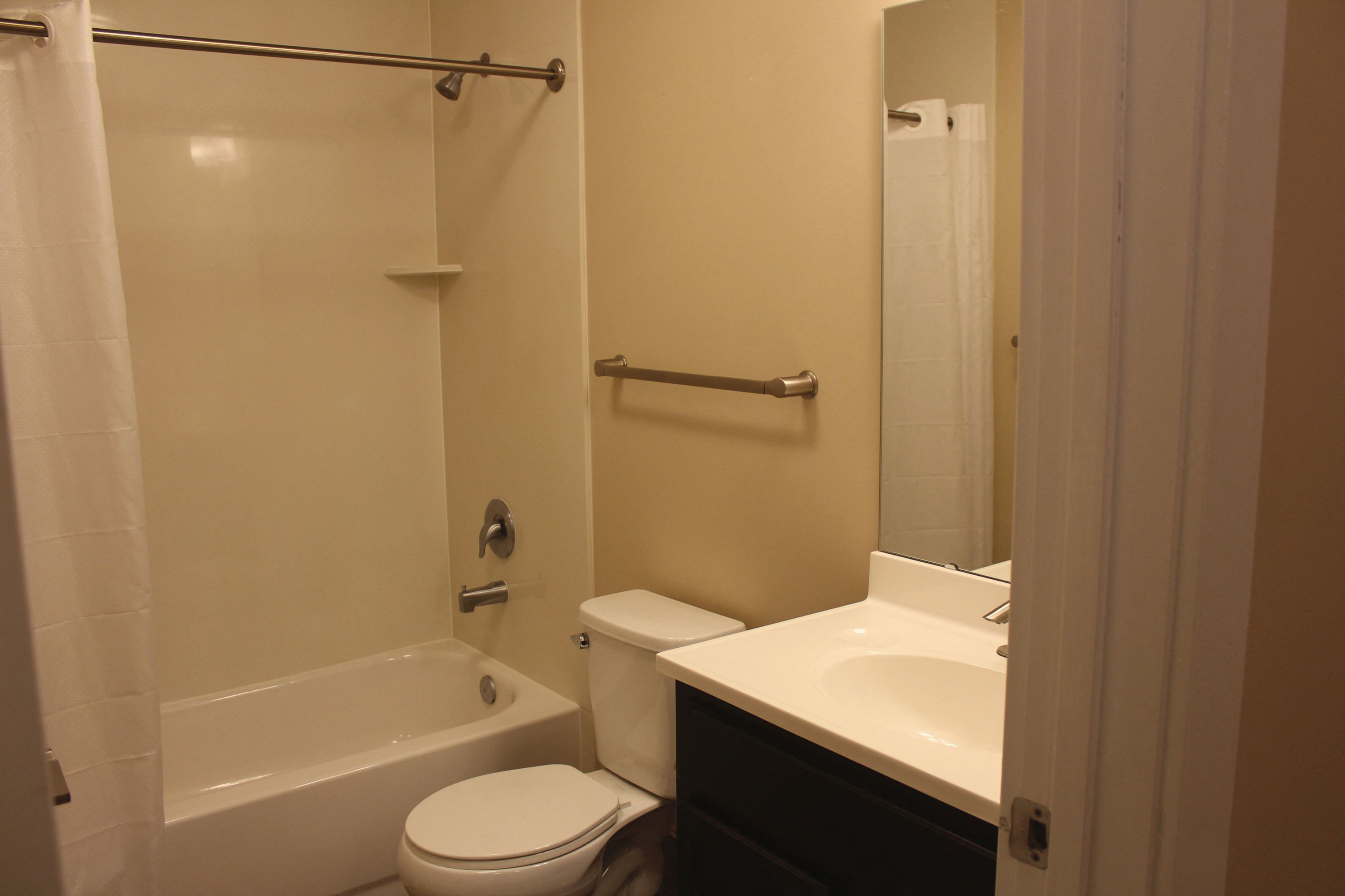 A white toilet is in a bathroom with a white sink and a white bathtub.