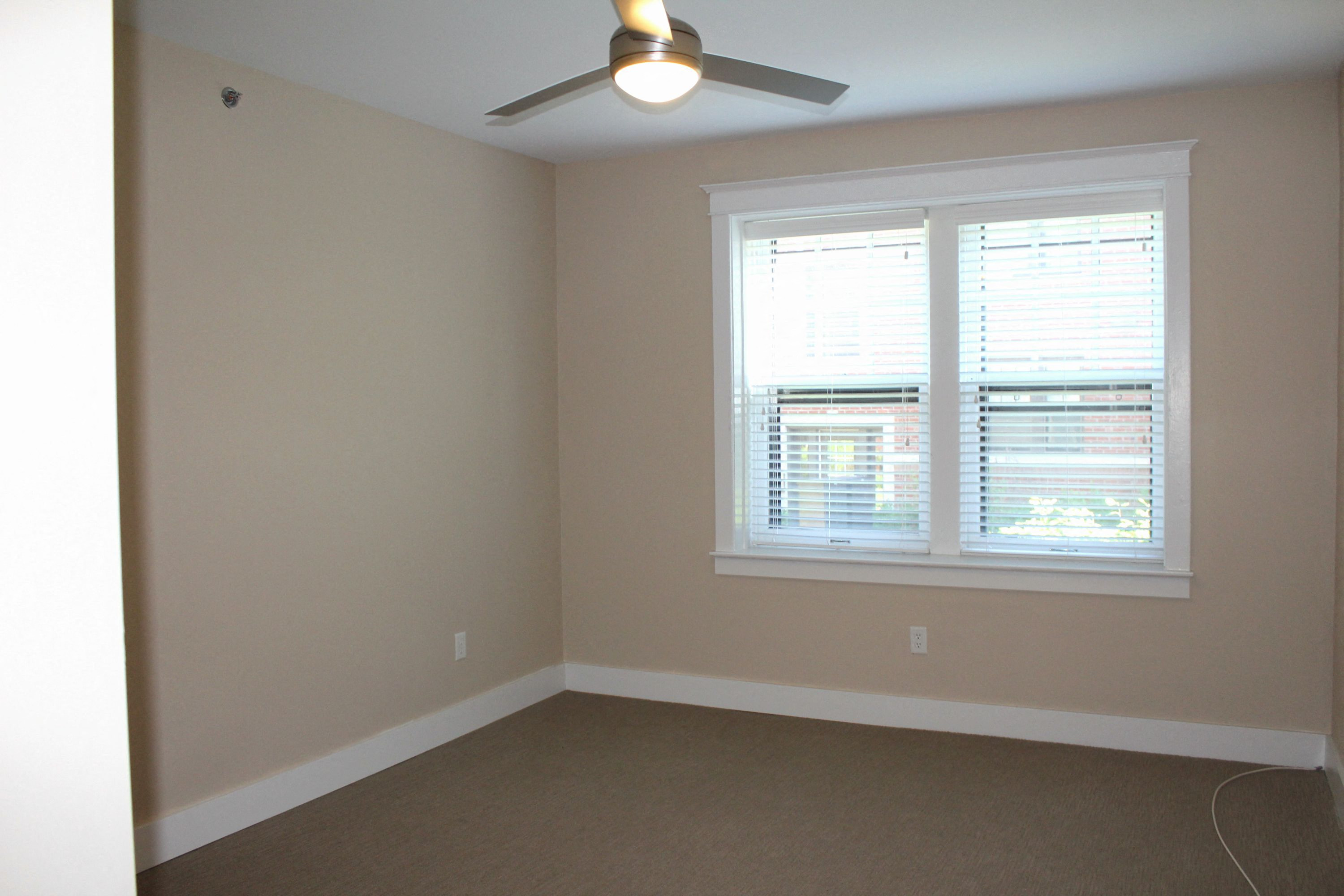 A room with a window and a ceiling fan.
