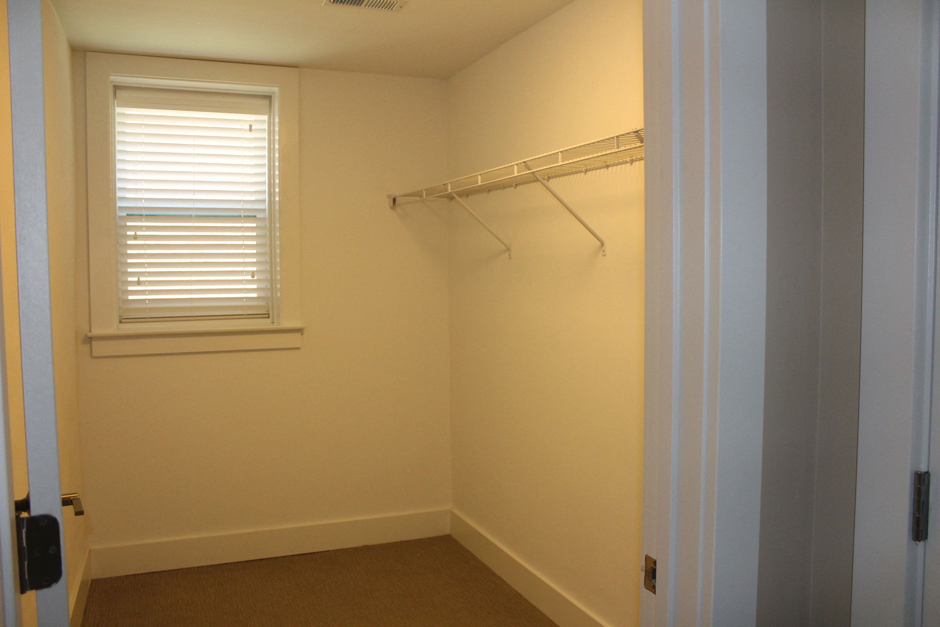 A white closet with a window and a shelf.