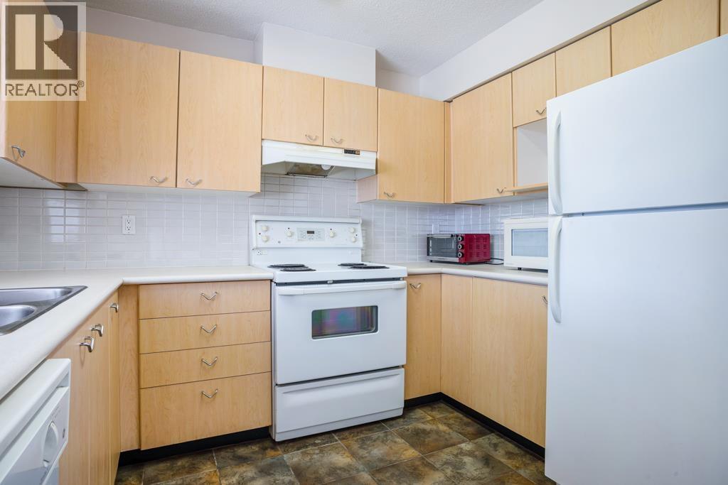 A kitchen with wooden cabinets and white appliances.