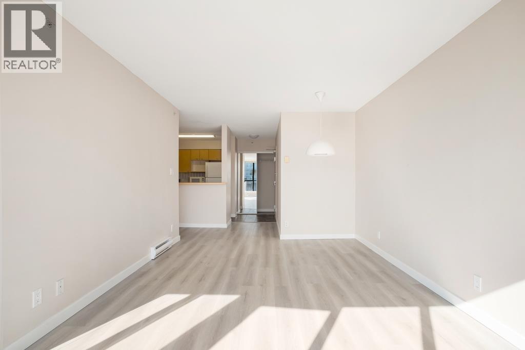 A spacious room with wooden flooring and white walls, with a doorway leading to another room.