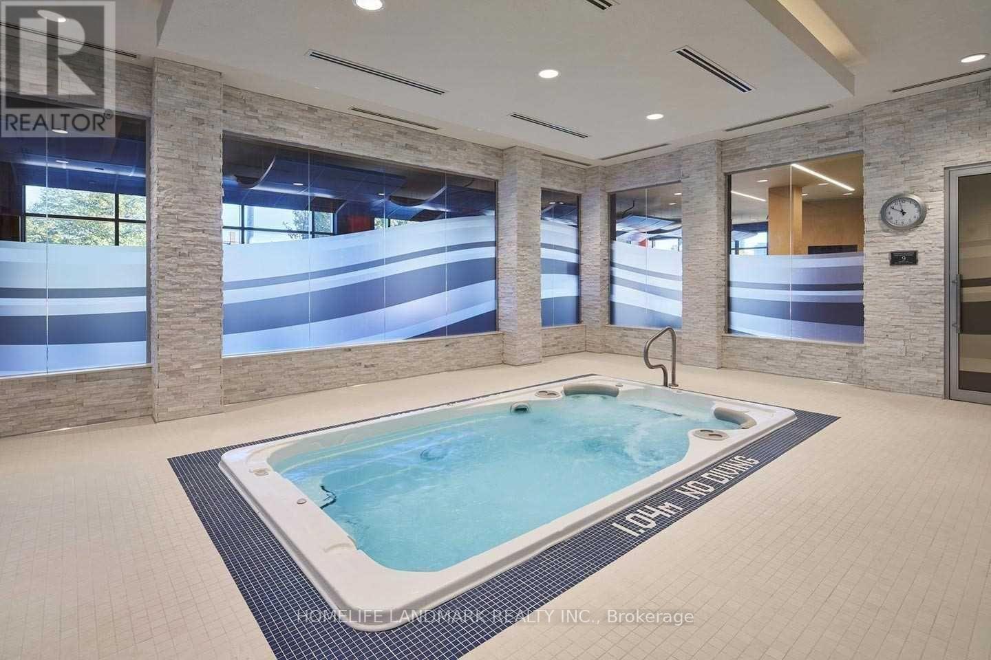 A hot tub in a room with a clock on the wall.