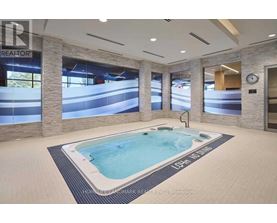 A hot tub in a room with a clock on the wall.