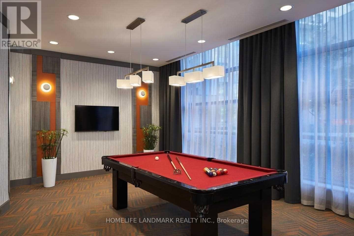 A pool table in a room with a television and a plant.