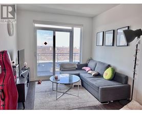 A living room with a grey couch, a glass table, a red sculpture, and a view of the city through the window.