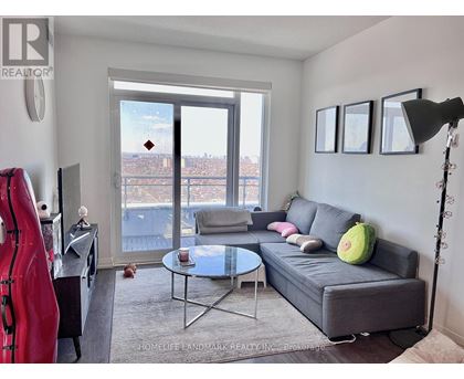 A living room with a grey couch, a glass table, a red sculpture, and a view of the city through the window.