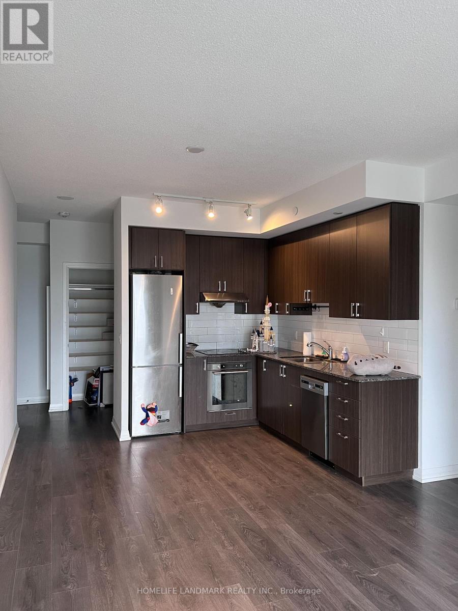 A modern kitchen with dark wood floors and stainless steel appliances.