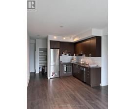A modern kitchen with dark wood floors and stainless steel appliances.