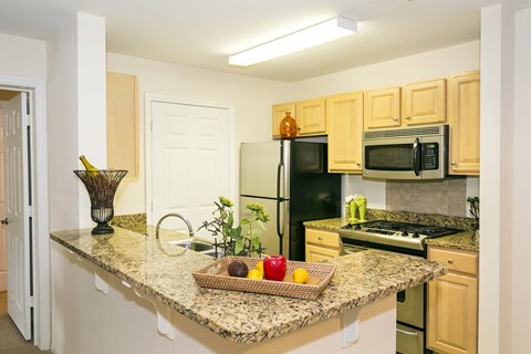 A kitchen with granite countertops and wooden cabinets.