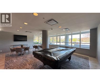 A pool table is in the middle of a room with a large window.