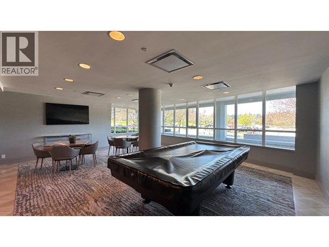 A pool table is in the middle of a room with a large window.