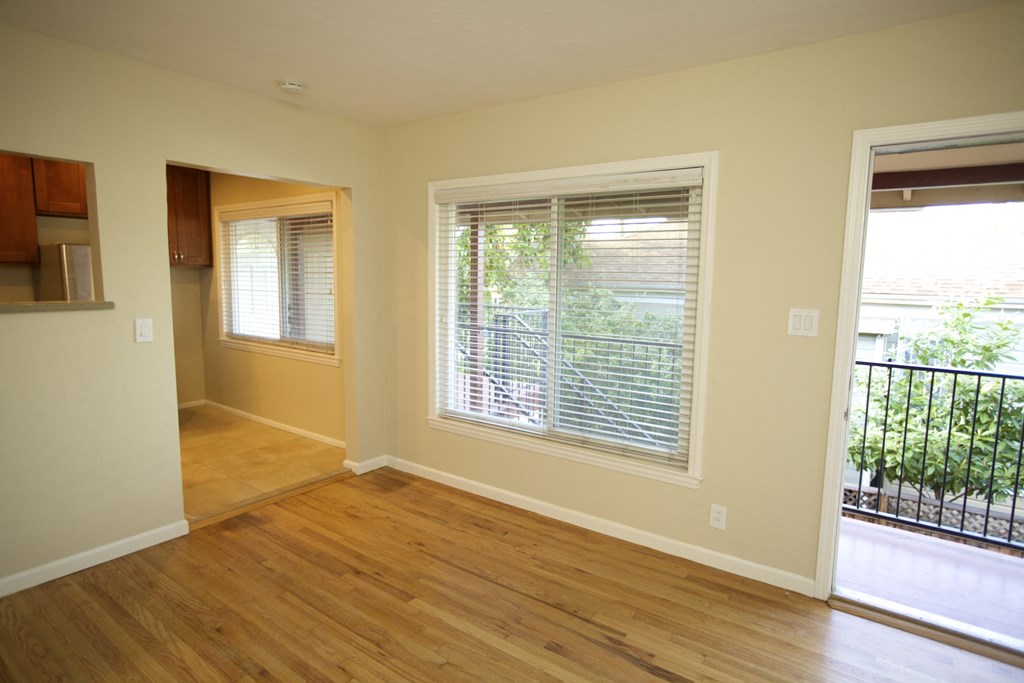 an empty living room with a large window and a wooden floor