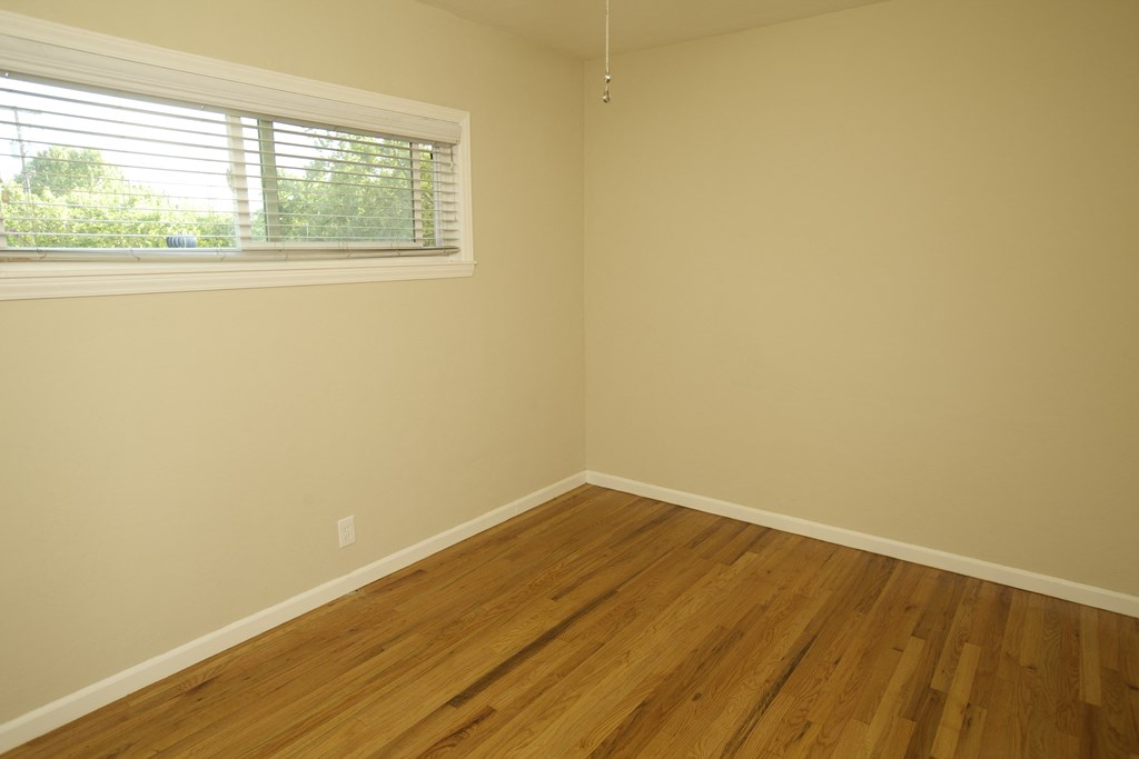 an empty room with a window and wooden floors