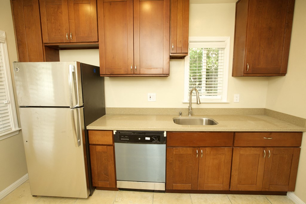 a kitchen with wooden cabinets and a stainless steel refrigerator