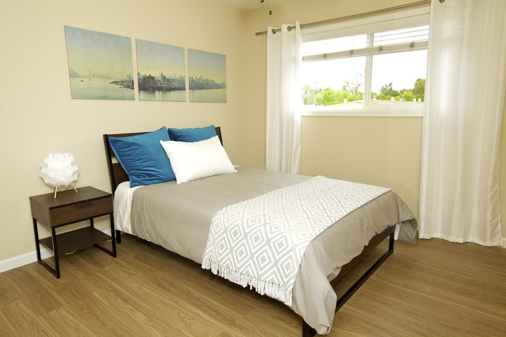 a bedroom with a bed with white sheets and blue pillows