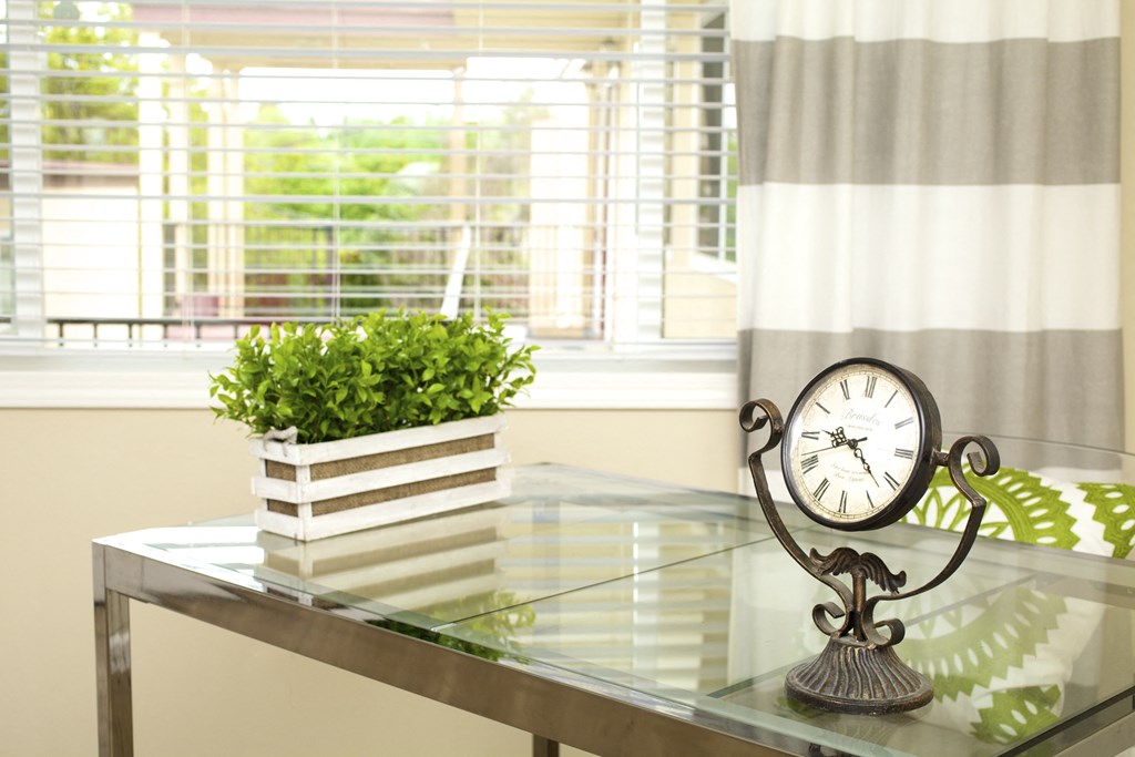 a glass table with a clock and a plant on it