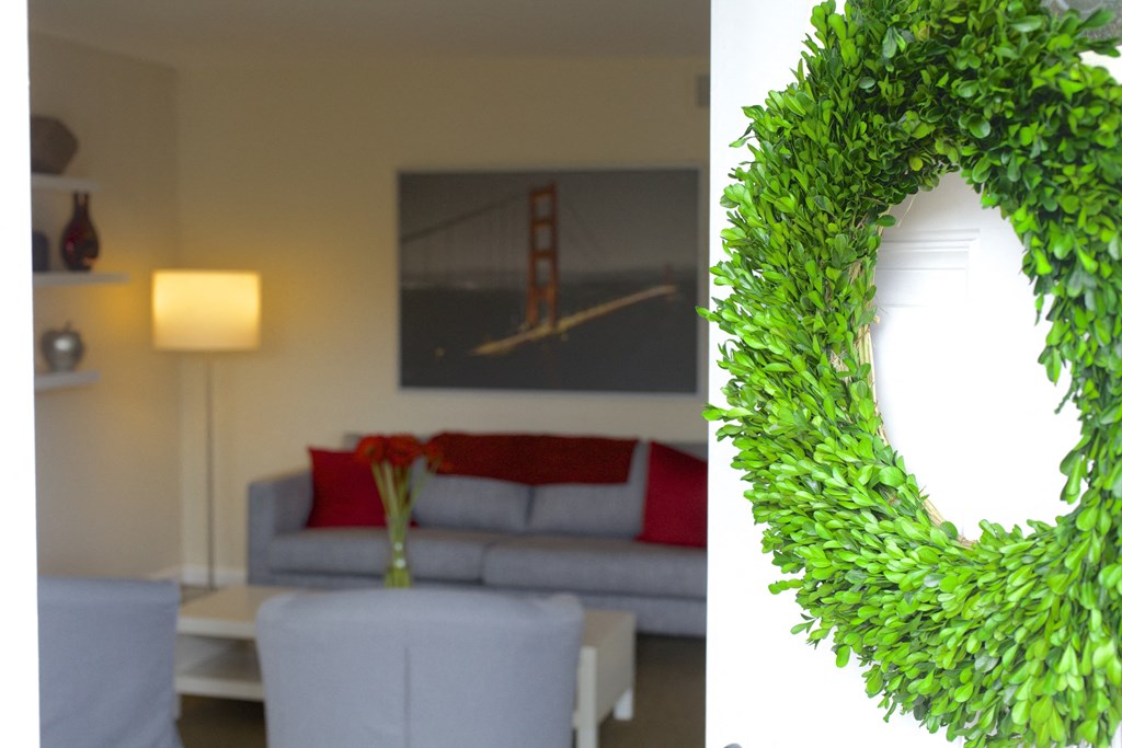 a living room with white furniture and a green wreath