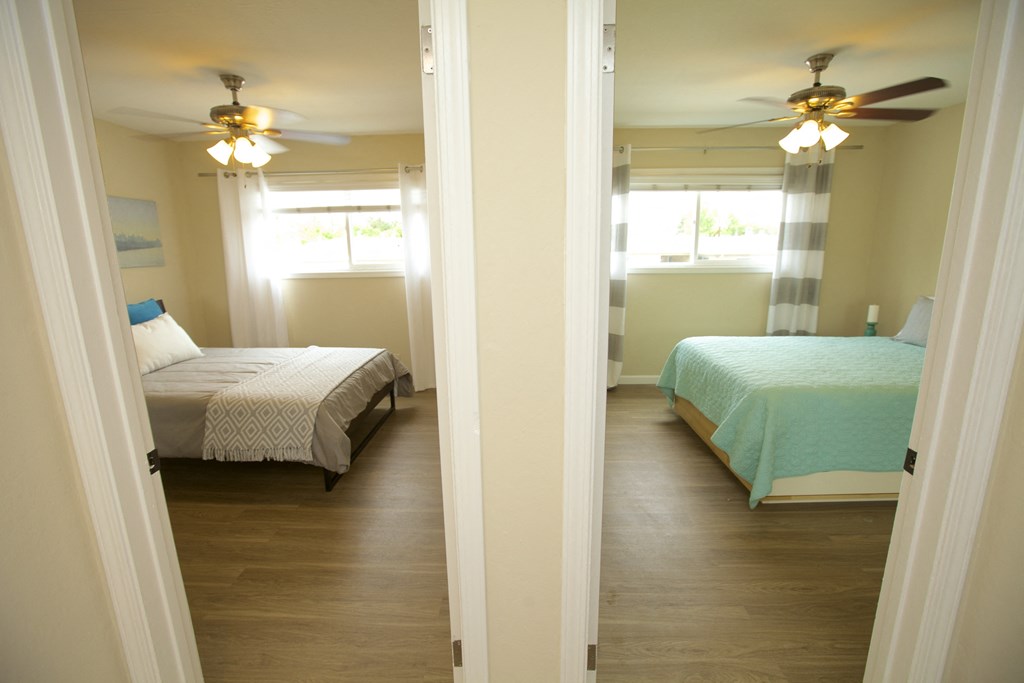 a bedroom with two beds and two ceiling fans