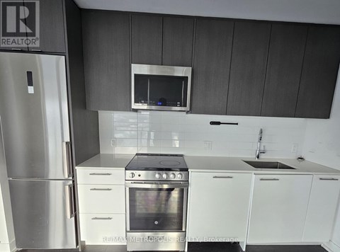 A kitchen with a stainless steel refrigerator and white cabinets.