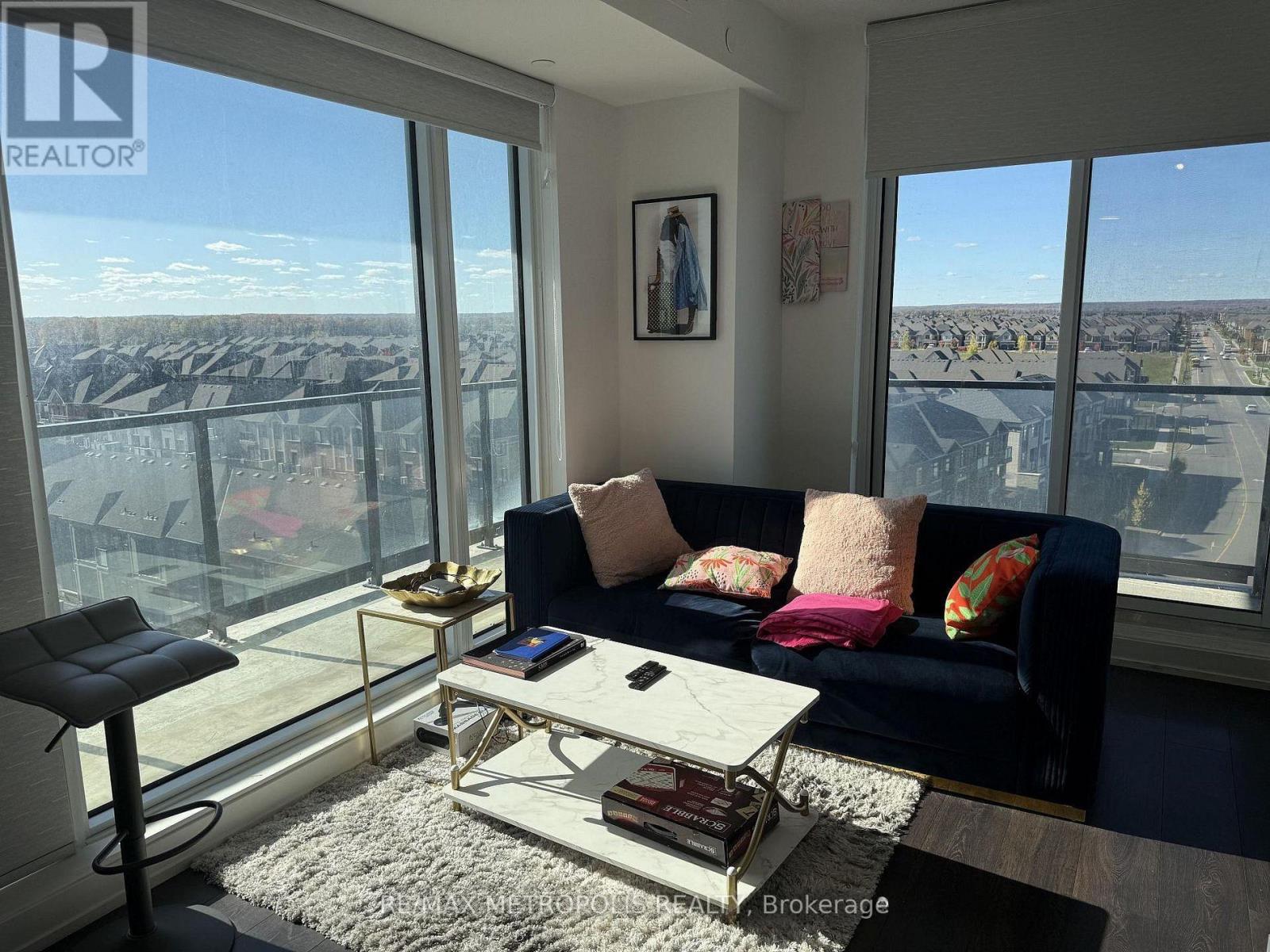 A living room with a couch, a chair, a coffee table, and a view of the city.
