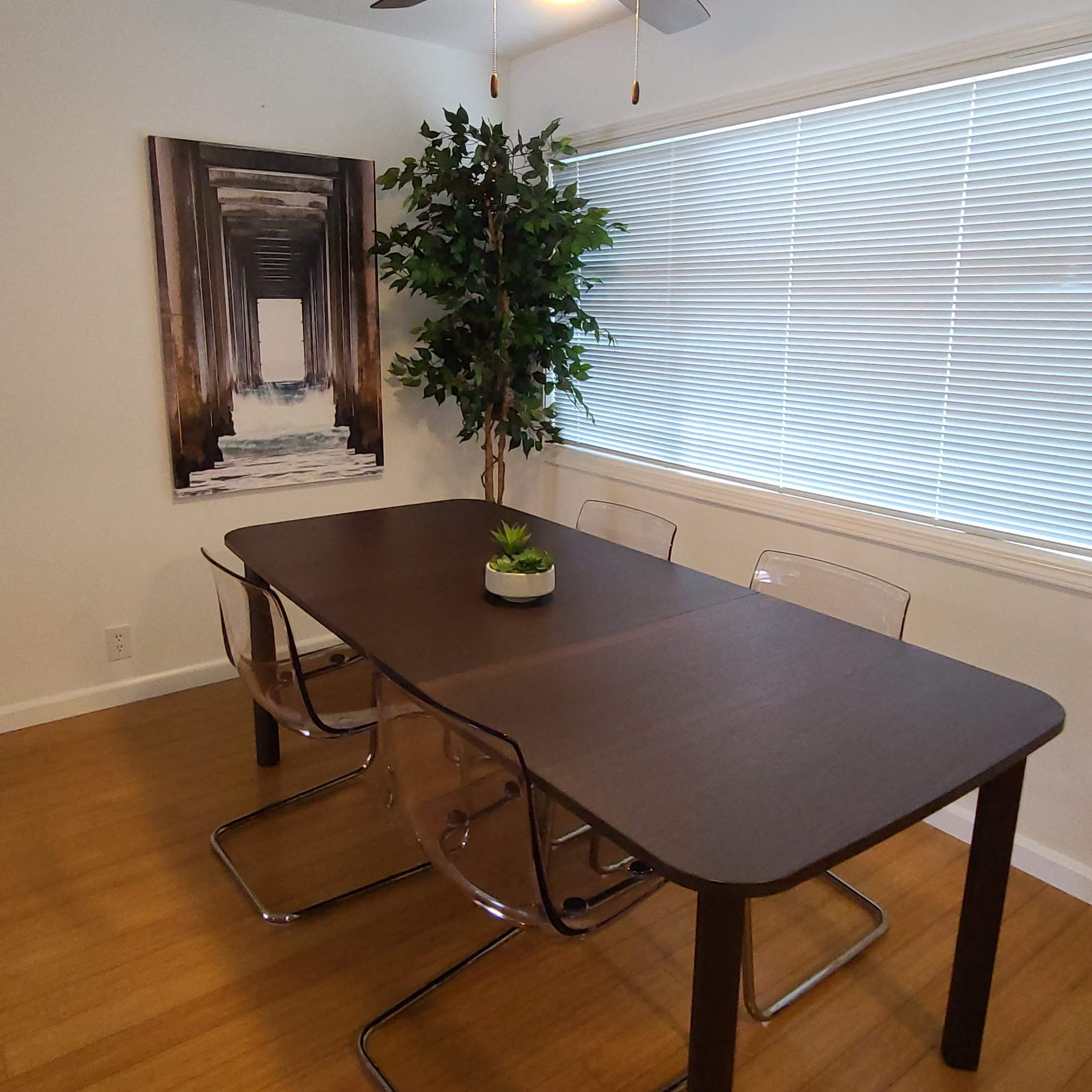 a dining room with a table and a potted plant in front of a window