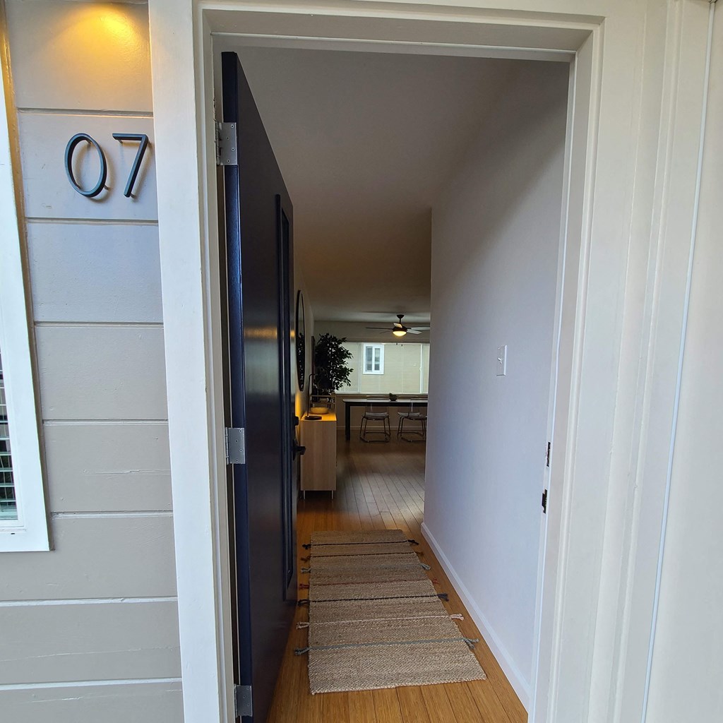 a hallway with a door open to a kitchen and a dining room