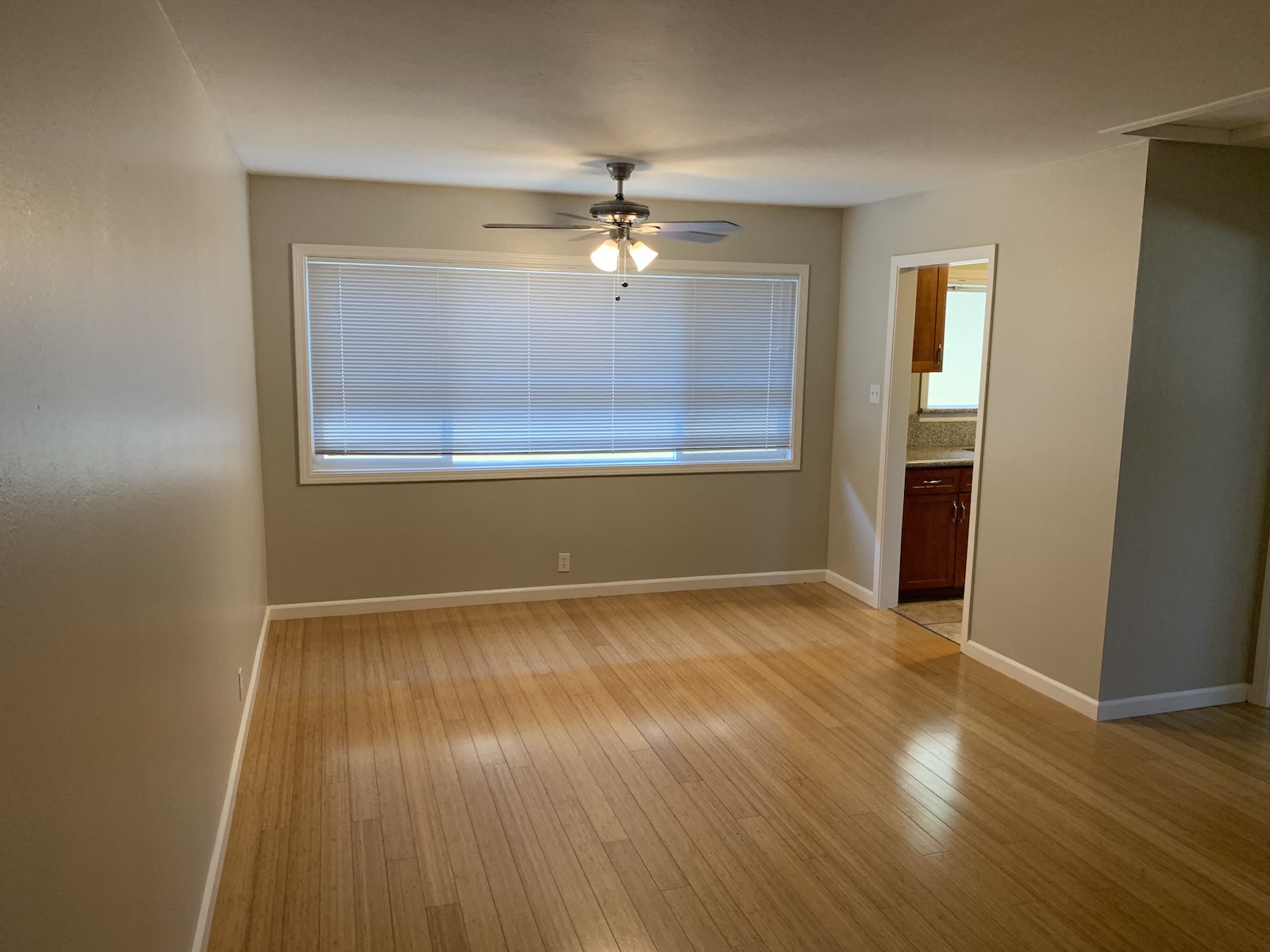 an empty living room with a window and a ceiling fan