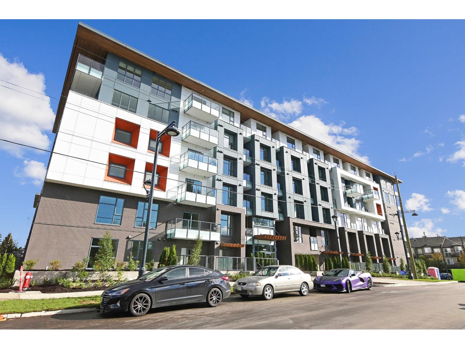 A modern apartment building with cars parked in front.
