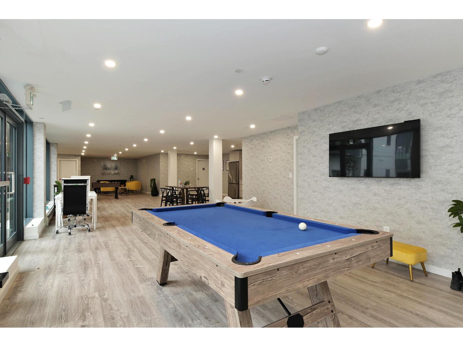A pool table is in the middle of a room with a TV on the wall.