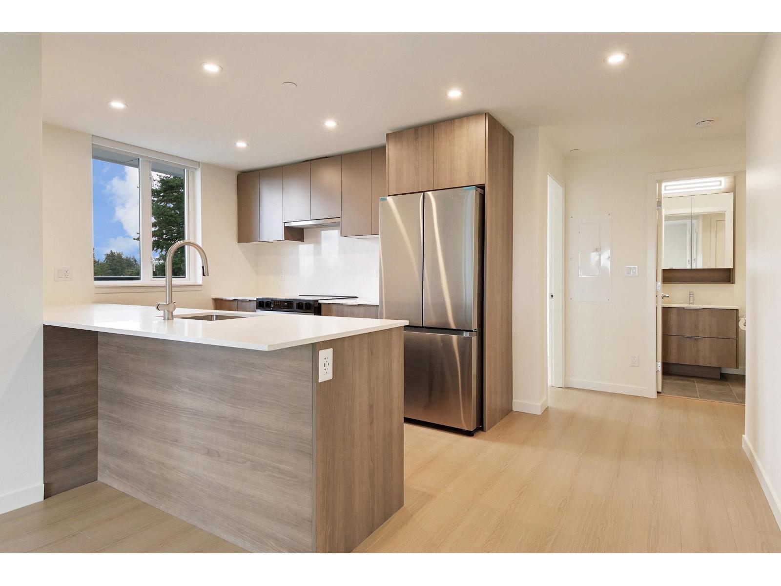 A modern kitchen with a stainless steel refrigerator and wooden cabinets.