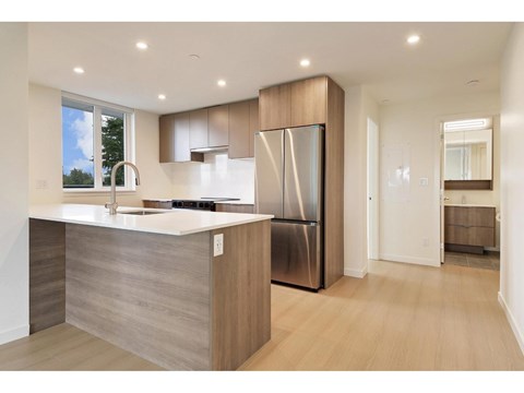 A modern kitchen with a stainless steel refrigerator and wooden cabinets.
