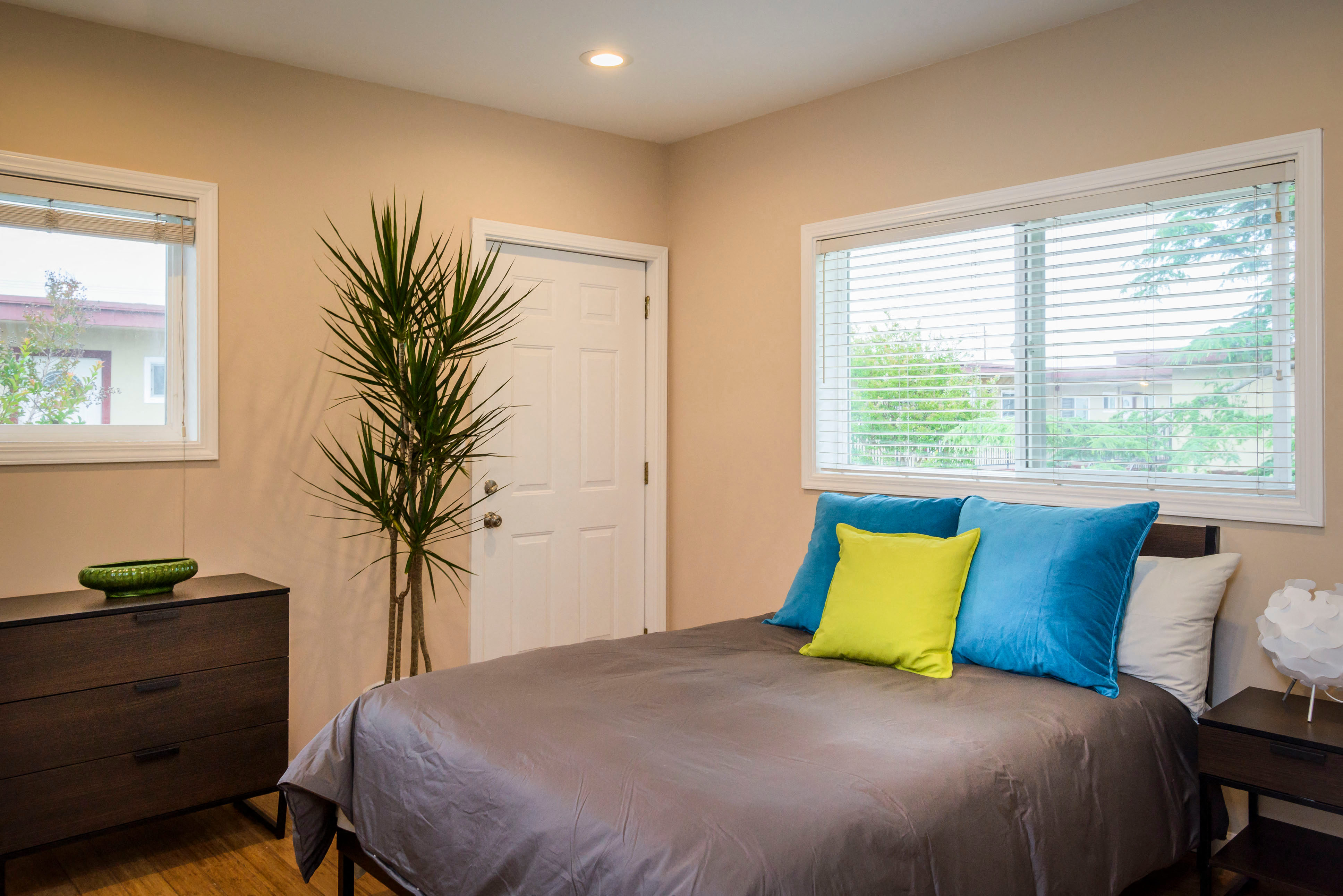 a bedroom with a bed with blue and yellow pillows on it and a dress