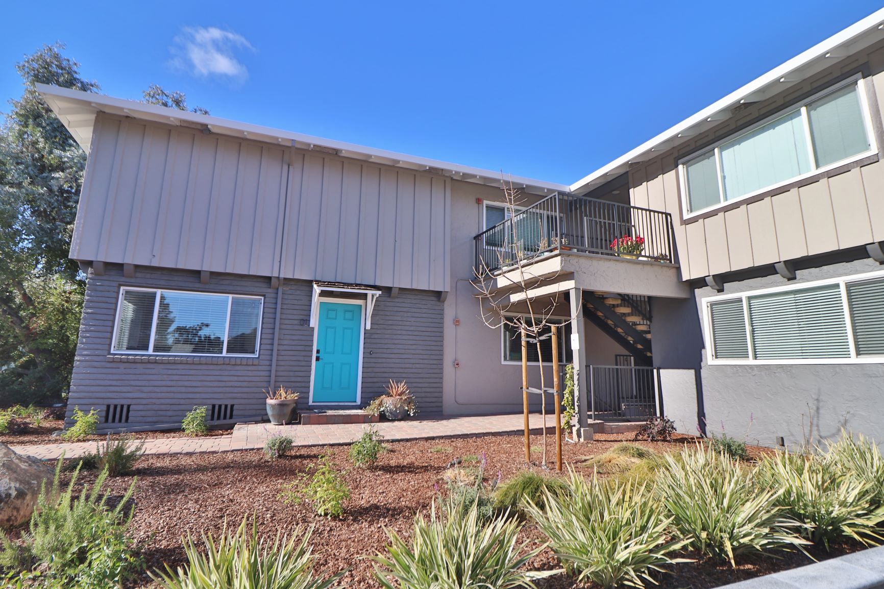 the front of a gray house with a blue door