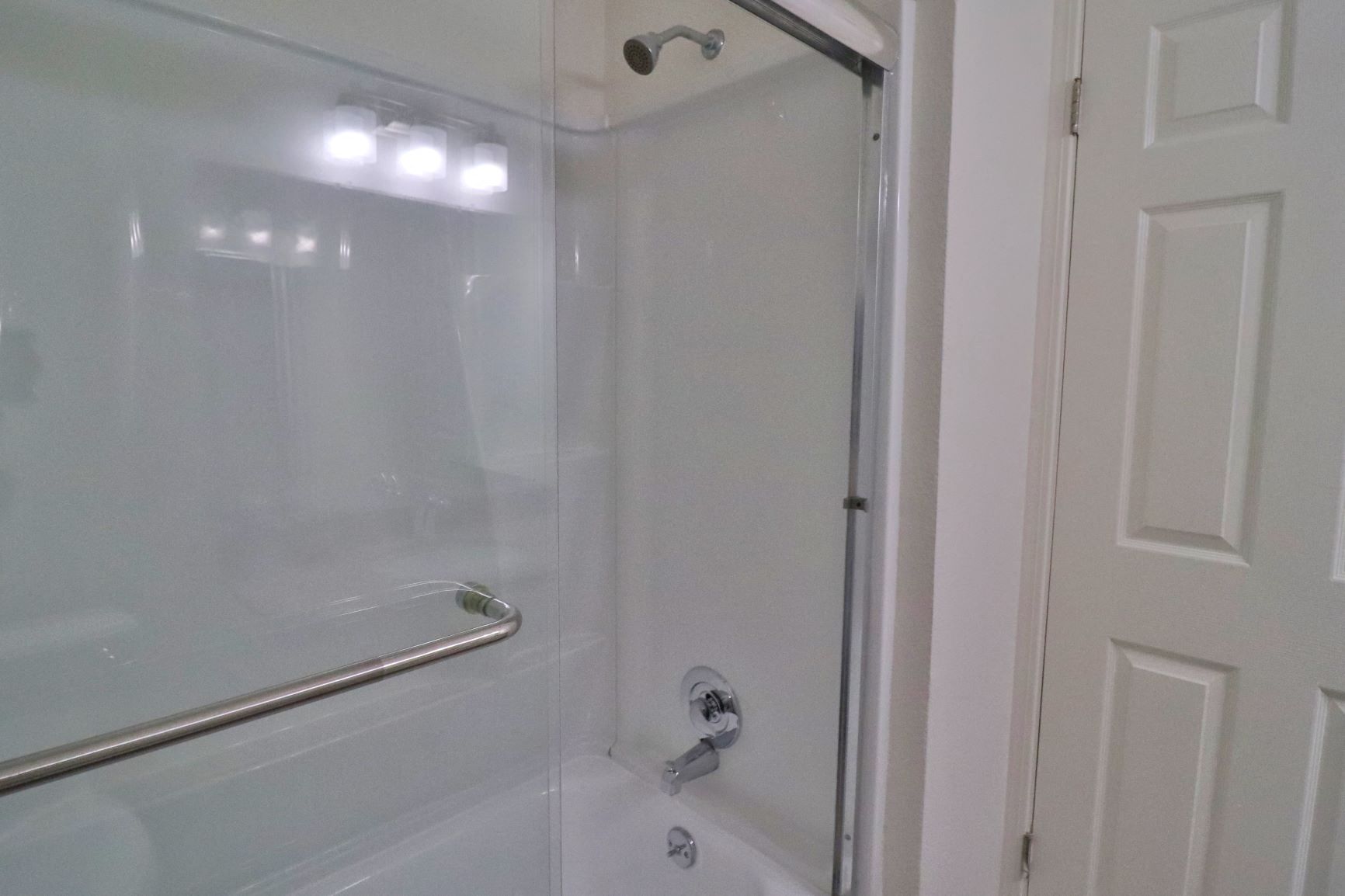 a bathroom with a shower and a tub and a door