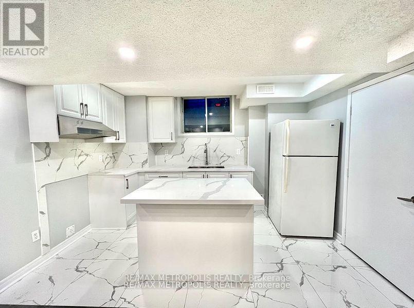 A white kitchen with a marble floor and a fridge.