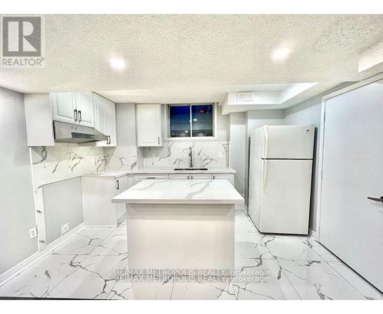 A white kitchen with a marble floor and a fridge.