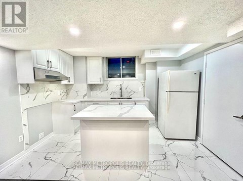 A white kitchen with a marble floor and a fridge.